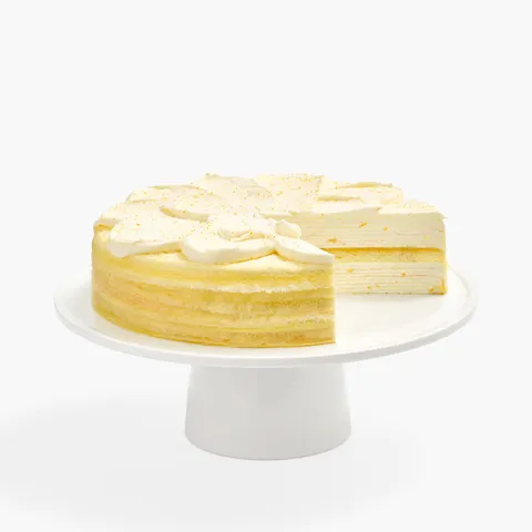 A sliced into Lady M Orange Mille Crepes cake on a white cake stand.