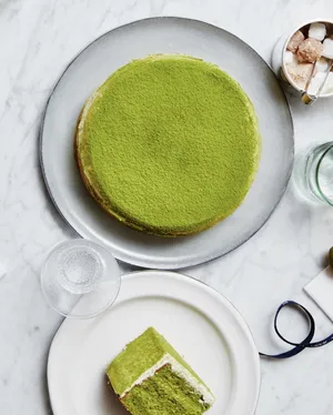 Flat lay image of Lady M's large Green Tea Mille Crêpes with a slice of Green Tea Mousse.