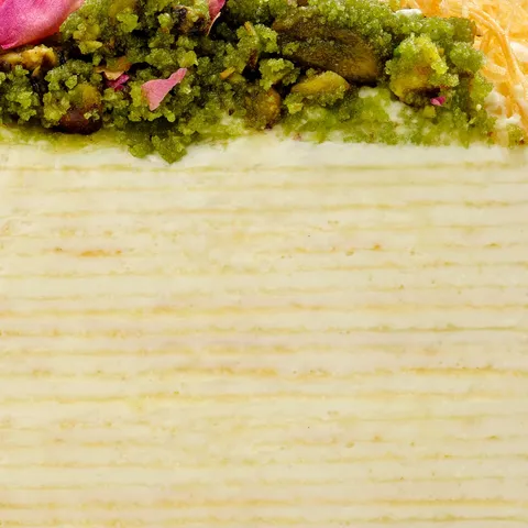 Close-up of Lady M's Baklava Mille Crêpes layers with crêpes, cream, pistachio, rose, and kataifi.
