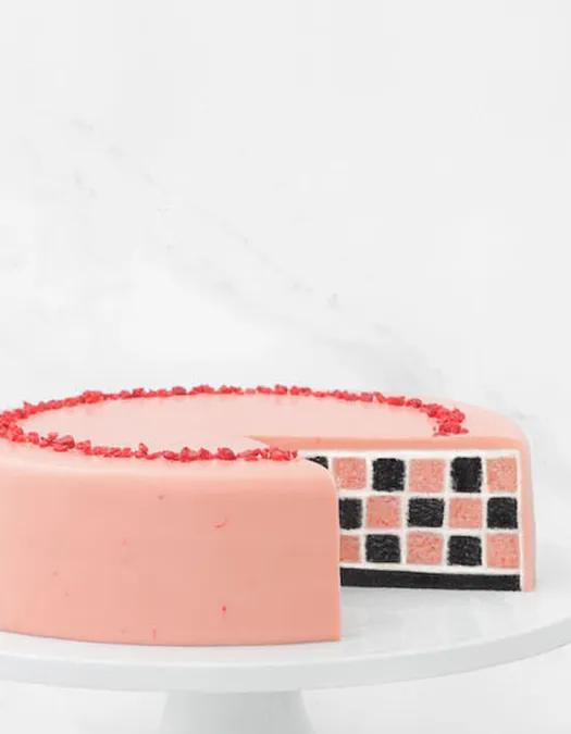 Lady M's Pink Checkers on a white cake stand against a marble background.