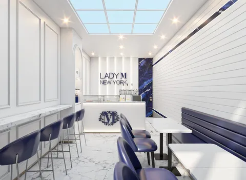 Interior of a modern Lady M New York cafe featuring a bright white and deep blue design with marble floors and cafe seating.