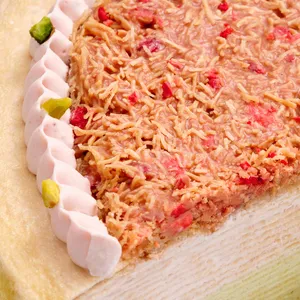 Macro detail of strawberry-pistachio kataifi topping with freeze-dried strawberries and cream border.