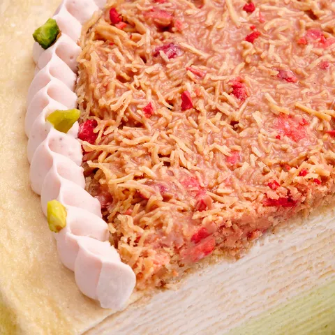 Macro detail of strawberry-pistachio kataifi topping with freeze-dried strawberries and cream border.