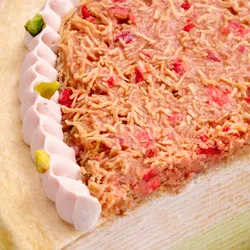 Macro detail of strawberry-pistachio kataifi topping with freeze-dried strawberries and cream border.