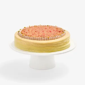 Whole Dubai Strawberry Mille Crêpes cake on a white cake stand.