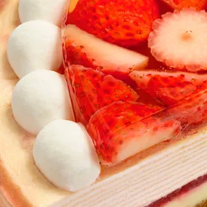Close-up of glazed strawberry topping and whipped cream dollops on cake edge