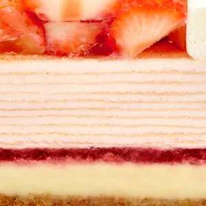 Close-up cross-section of crêpe layers, berry compote, and cheesecake base