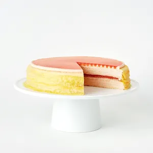 Guava Mille Crêpes cake sliced open on a white stand, revealing pink guava layers between delicate crêpes.