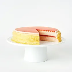 Guava Mille Crêpes cake sliced open on a white stand, revealing pink guava layers between delicate crêpes.