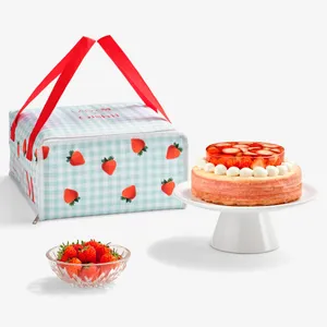 Lady M x Oishii cake carrier with strawberry gingham print, displayed next to a Berry Trois Mille Crêpes cake and fresh strawberries.