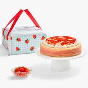 Lady M x Oishii cake carrier with strawberry gingham print, displayed next to a Berry Trois Mille Crêpes cake and fresh strawberries.