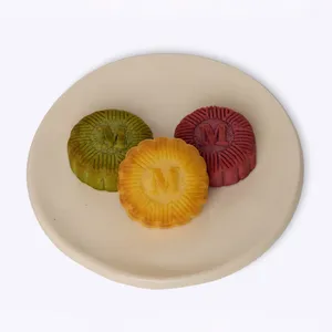 Three Lady M mooncakes in pistachio, yuzu cheesecake, and red bean on a round plate.