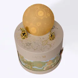 Lady M gift box with glowing moon topper in warm ambient lighting.