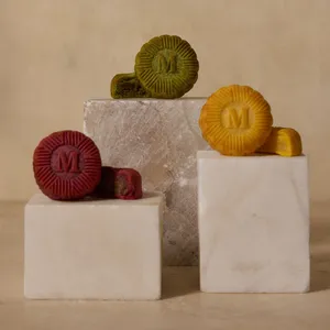 Three Lady M mooncakes in pistachio, custard, and red bean on marble blocks