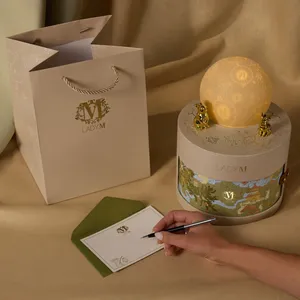 Lady M gift bag, glowing gift box, and hand writing on a personalized notecard