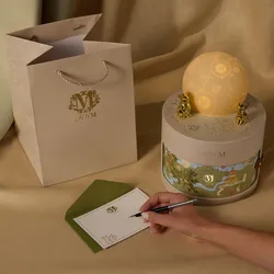 Lady M gift bag, glowing gift box, and hand writing on a personalized notecard