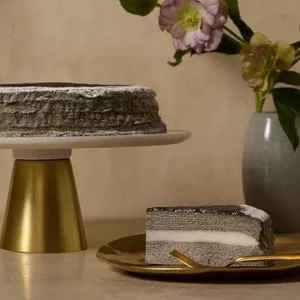 Sliced Sesame Mochi Mille Crêpes cake with mochi center and a whole cake on gold stand in the background.