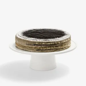 Whole Sesame Mochi Mille Crêpes cake on white stand, powdered sugar dusted top