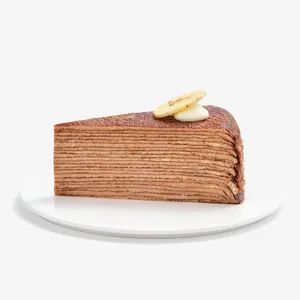 Single slice of Chocolate Banana Mille Crêpes topped with banana chip and cream