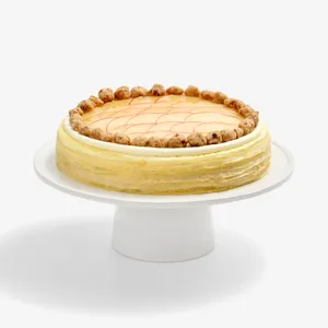 Whole Apple Pie Mille Crêpes topped with fanned apple slices and crumble on a white stand