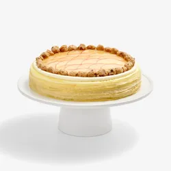 Whole Apple Pie Mille Crêpes topped with fanned apple slices and crumble on a white stand