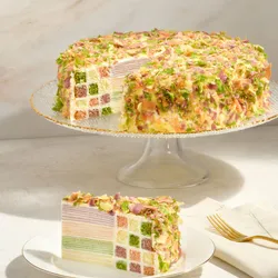 Lady M Birthday Cake 9" on a cake stand with a slice showing checkerboard sponge and crêpe layers