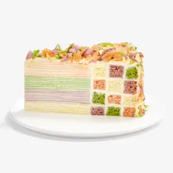 Slice of Lady M Birthday Cake showing rainbow crêpe layers and checkerboard sponge
