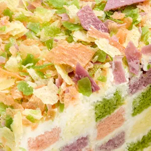 Close-up of colorful crêpefetti topping over checkerboard sponge on the Lady M Birthday Cake 6"